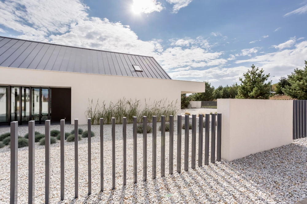 Moderner Metallzaun (Zäune) umgibt neu gestaltete Kiesfläche vor modernem Wohnhaus