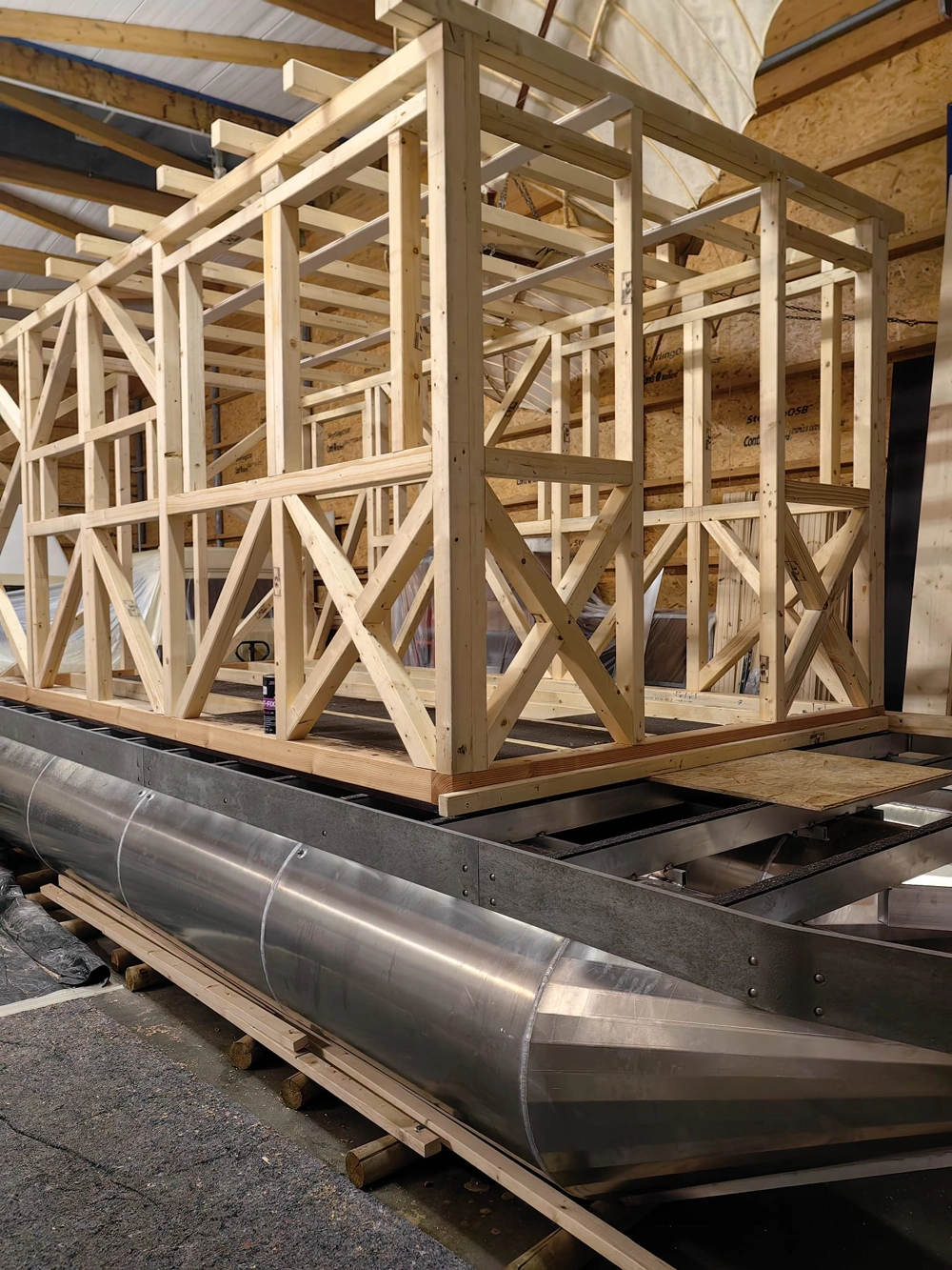 Rohbau eines Hausboots: Holzständerkonstruktion auf Aluminiumpontons im Hallenbau