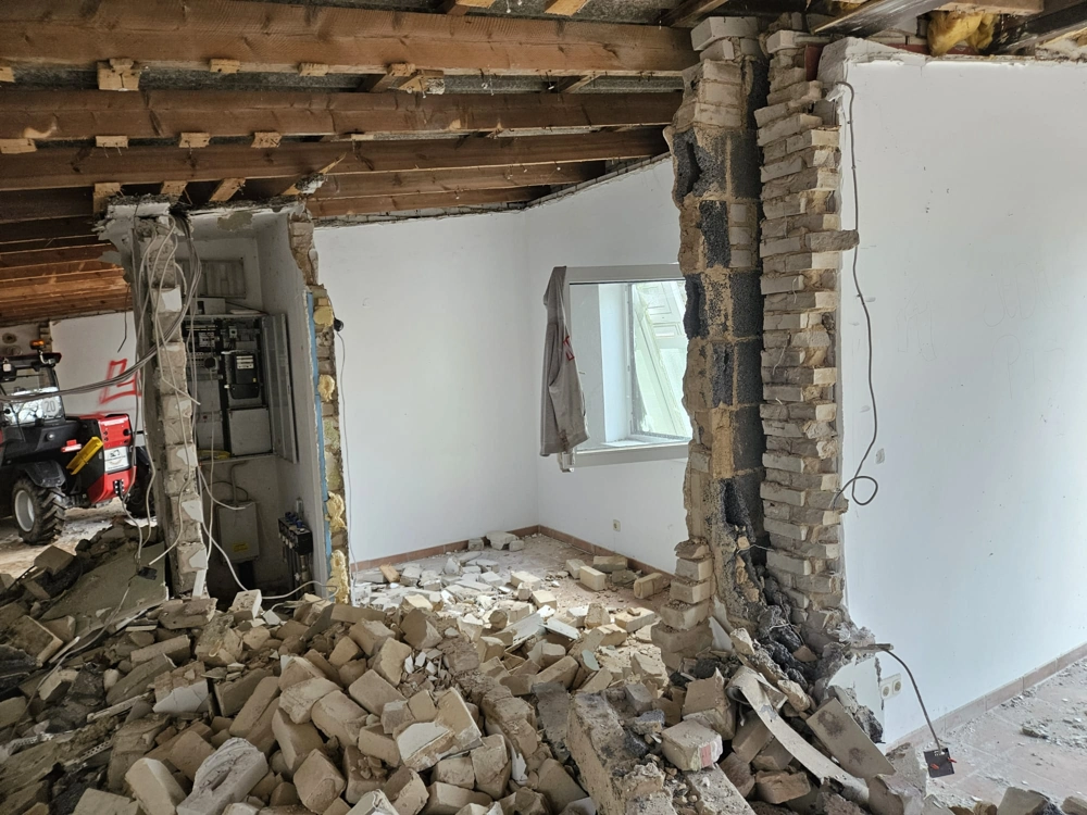 Renovierung: Abbruch einer Innenwand mit Ziegeltrümmern und freigelegten Deckenbalken