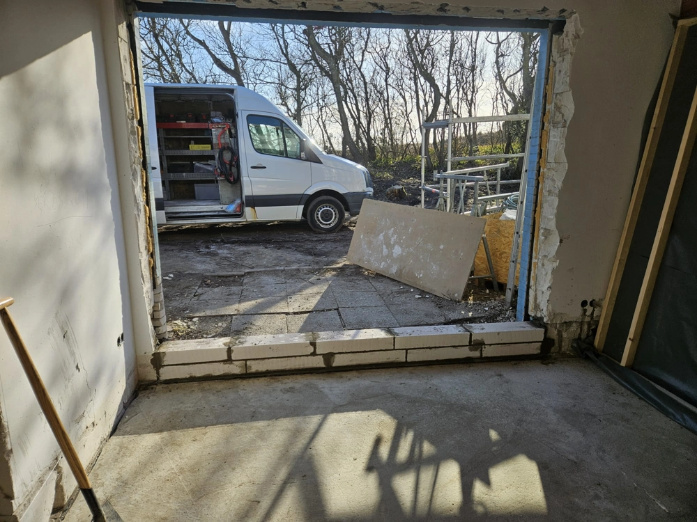 Innenansicht einer Baustelle mit neuem Türdurchbruch und Trockenbauarbeiten im Rohbau