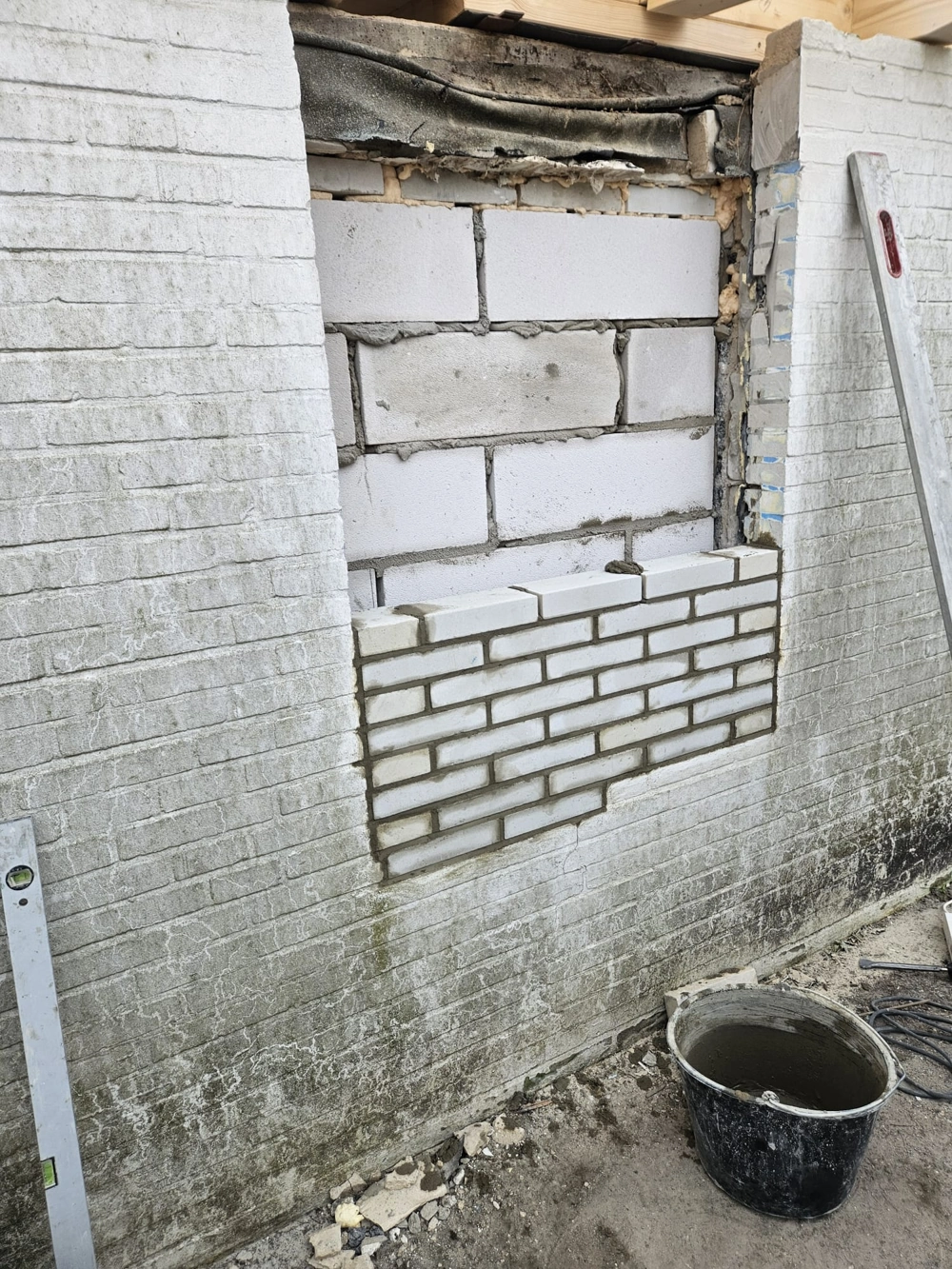 Wandöffnung wird mit Mauersteinen und Mörtel verschlossen im Rahmen der Renovierung