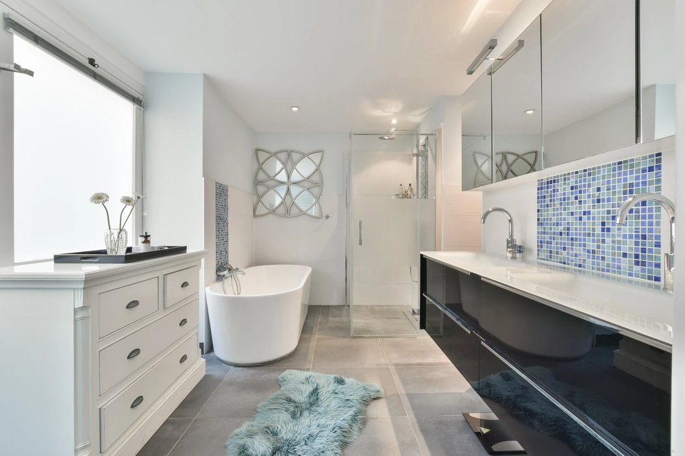 Renoviertes Badezimmer nach Badezimmer renovieren mit freistehender Badewanne, Glasdusche, Doppelwaschtisch und grauem Fliesenboden