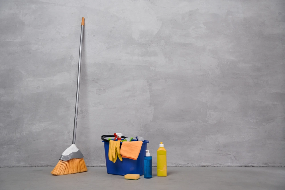 Besen, Eimer mit Putzutensilien, Handschuhe und Reinigungsmittel für Unterhaltsreinigung