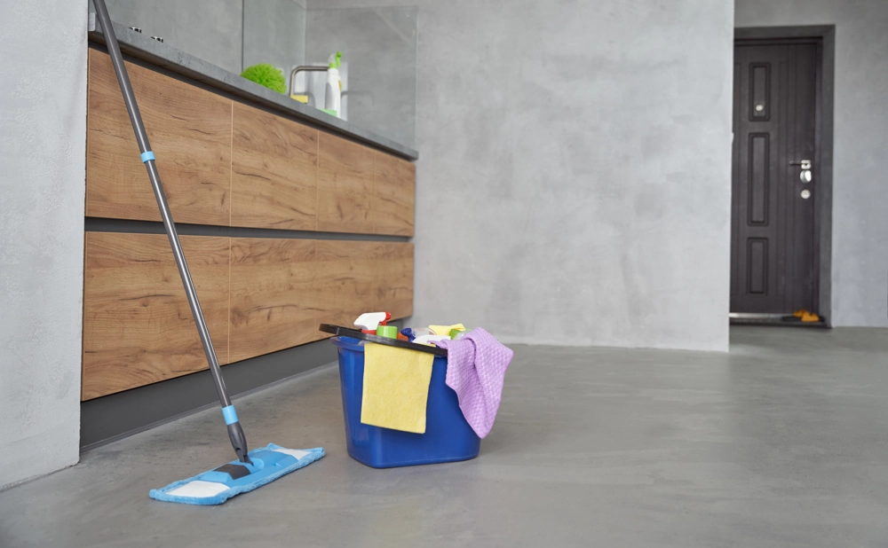 Eimer mit Reinigungsmitteln und Mop vor Küchenzeile für Unterhaltsreinigung