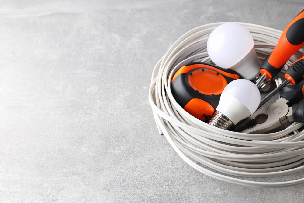 Werkzeug und Kabel für Elektroinstallationen: Kabelrolle, LED-Lampen, Schraubendreher und Zange