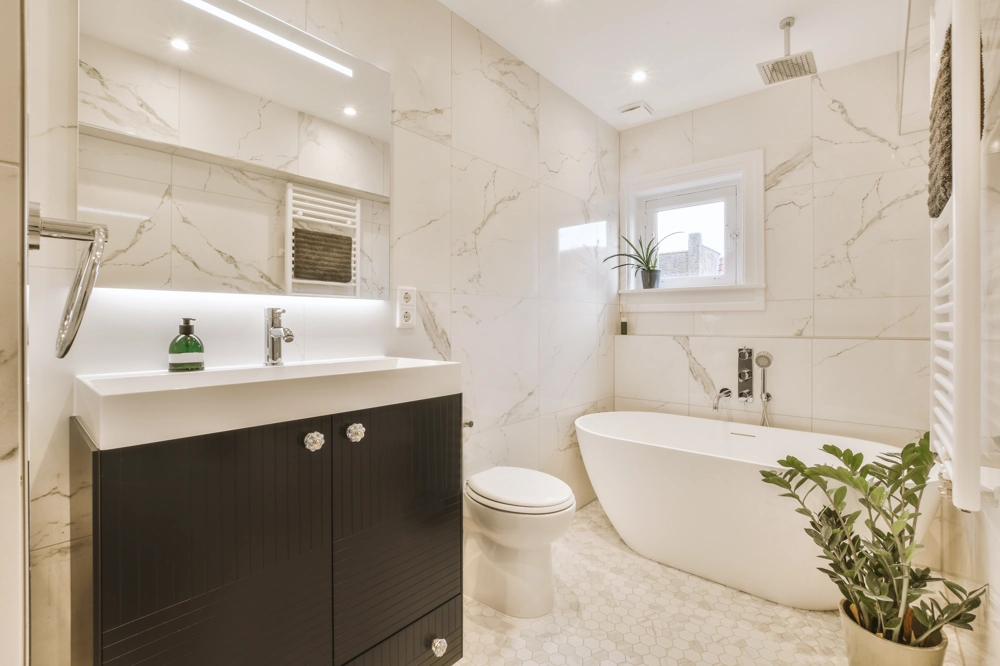 Modernes Badezimmer mit freistehender Badewanne, Waschtisch und Marmorfliesen für Badsanierung