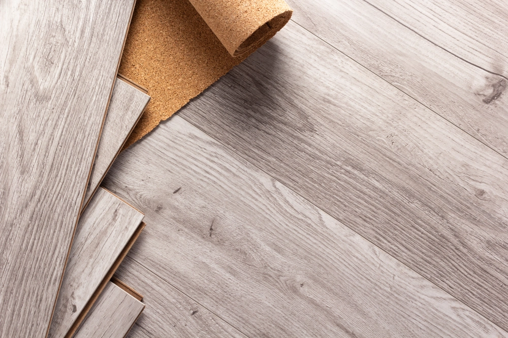 Korkunterlage und einzelne graue Vinyldielen in Holzoptik vor Verlegung für Vinylboden verlegen