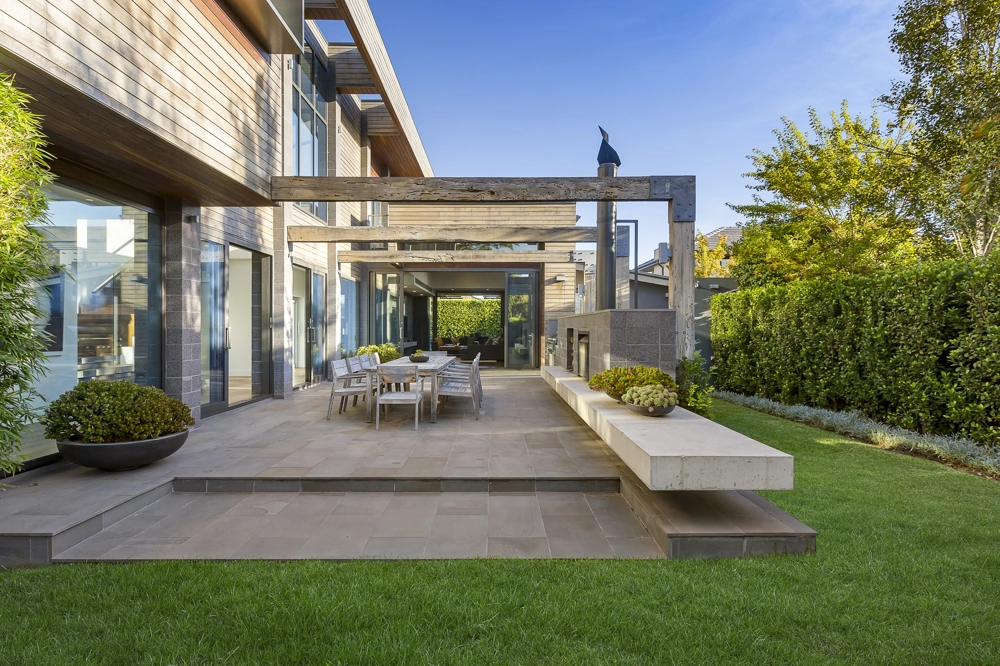 Moderne Terrasse mit überdachtem Sitzbereich, Betonbank und Gartenfläche zur Terrassengestaltung