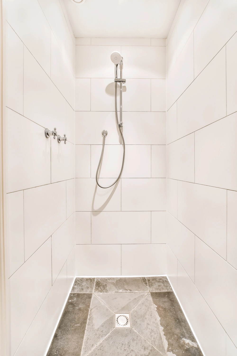 Dusche einbauen: modern geflieste Duschkabine mit weißen Wandfliesen und grauem Bodenbelag