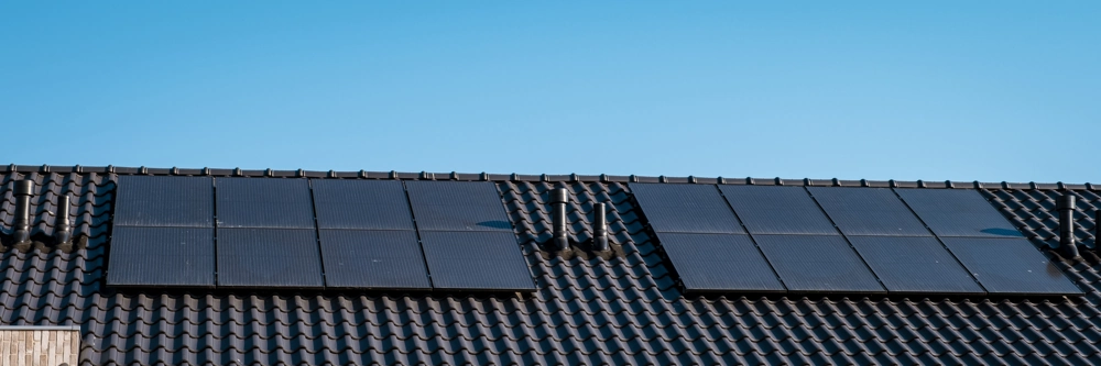 Photovoltaik montage auf dunklem Ziegeldach unter klarem Himmel