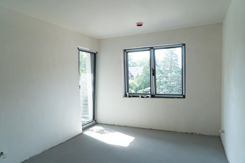 Frisch verputzter Neubau-Wohnraum mit Fensteröffnung und rohem Bodenuntergrund – Putzarbeiten