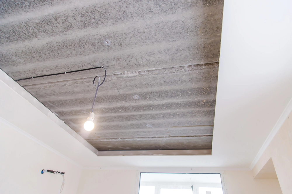 Unfertige abgehängte Decke mit freigelegten Trägern und hängender Lichtbirne, Decke abhängen