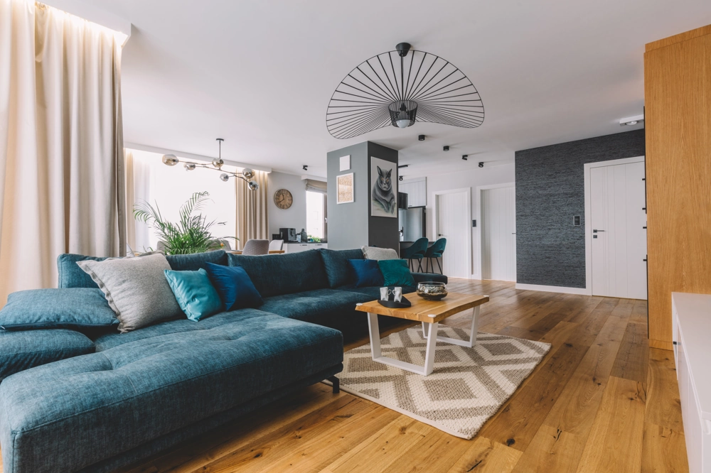 Modernes Wohnzimmer mit großem Ecksofa auf frisch verlegtem Parkettboden und Couchtisch