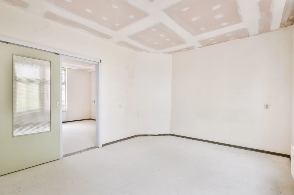 Leerer Raum mit ungestrichener Gipskartonverkleidung an Decke und Wänden nach Trockenbau